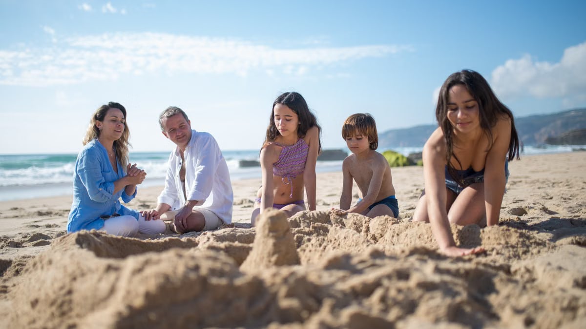 Family builds sandcastles while enjoying a sunny day at a beach in Portugal.
